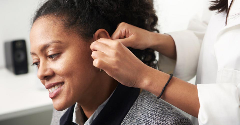 Image shows woman having her hearing aids repair/ adjustment