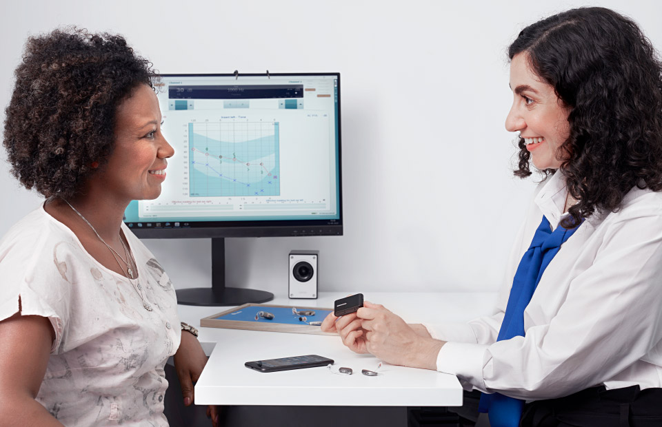 Image shows woman trying on hearing aids