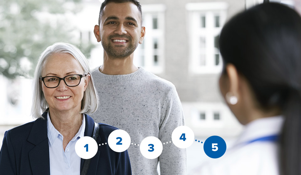 Image shows audiologist welcoming man and women in the hearing clinic