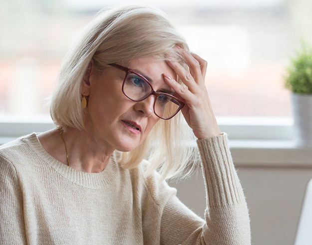 Image shows woman holding her head in pain